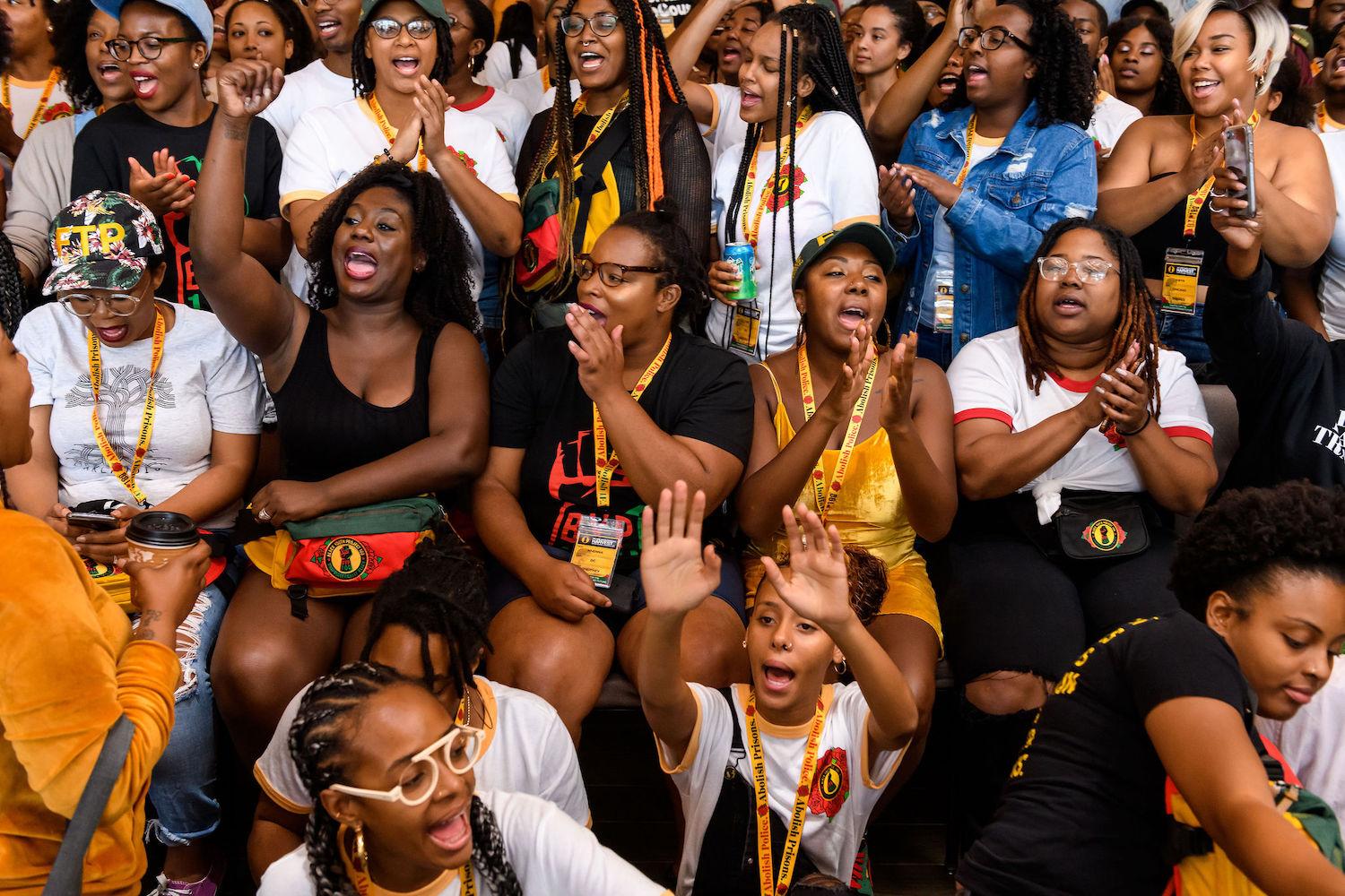 A group of black womxen cheer and clap at the Black Youth Project 100 National Convening. Photo taken by Christopher Jason.